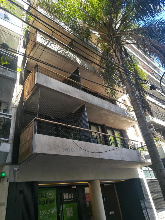 a building with a balcony and a palm tree at A Estrenar Estudio las Cañitas in Buenos Aires
