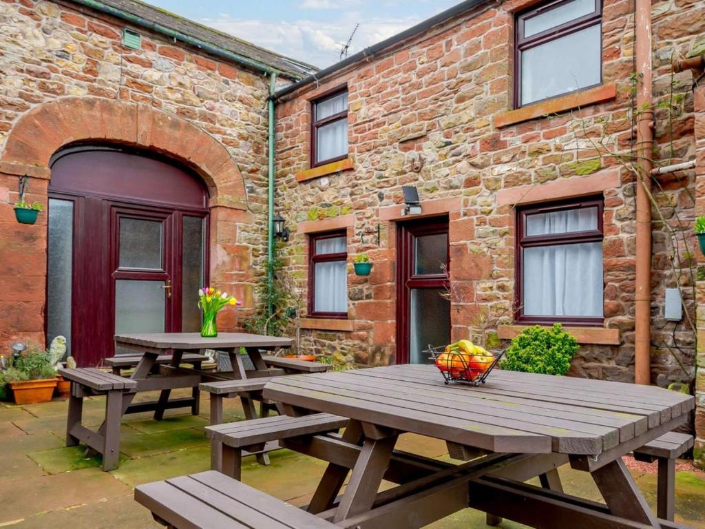 two wooden picnic tables in front of a brick building at 1 Bed in Penrith oc-90416 in Kirkoswald