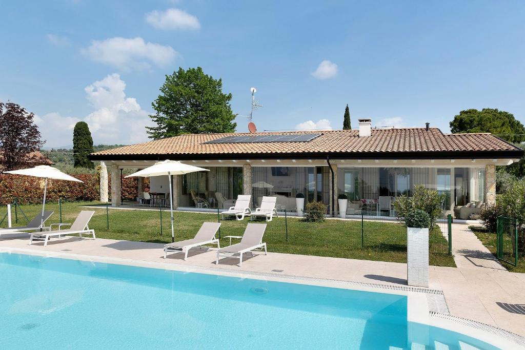 a villa with a swimming pool in front of a house at Bardolino Golden Hill in Bardolino