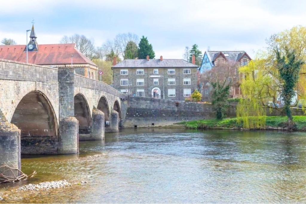 a bridge over a river with buildings in the background at The Lion Hotel in Builth Wells