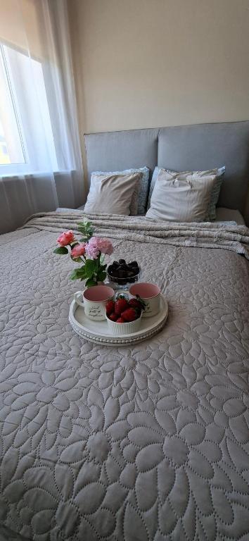 a bed with a tray of food and flowers on it at Laine Apartment in Pärnu