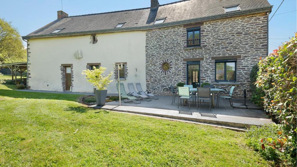 a house with a patio with chairs and a table at Mignonne en lisière de Brocéliande in Mauron