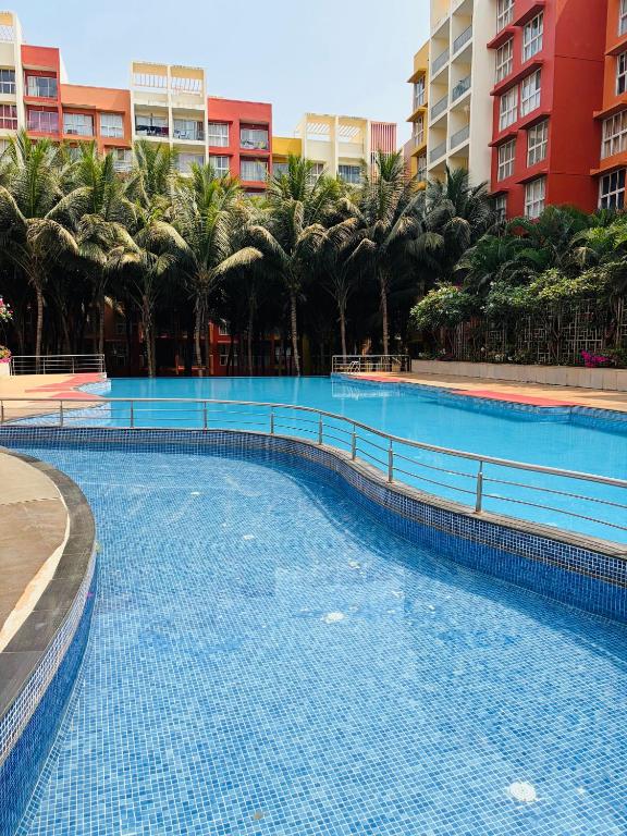 a large swimming pool with palm trees and buildings at Platinum - Sun-kissed Holidays Goa in Dabolim
