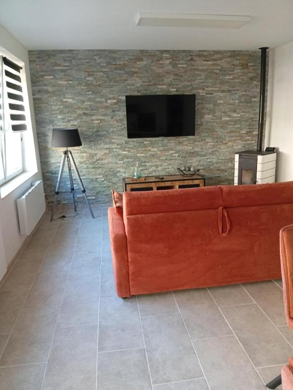 a living room with a couch and a tv on a brick wall at Le logis de la liane in Boulogne-sur-Mer