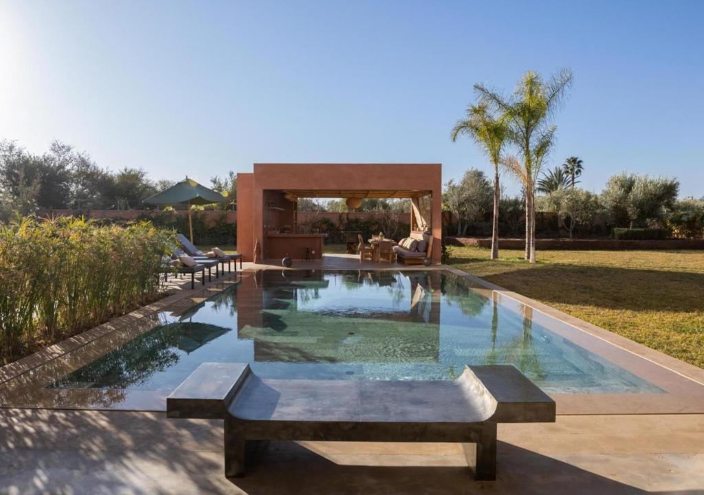 a swimming pool with a bench in a yard at Villa Émeraude 5 Ch in Marrakesh