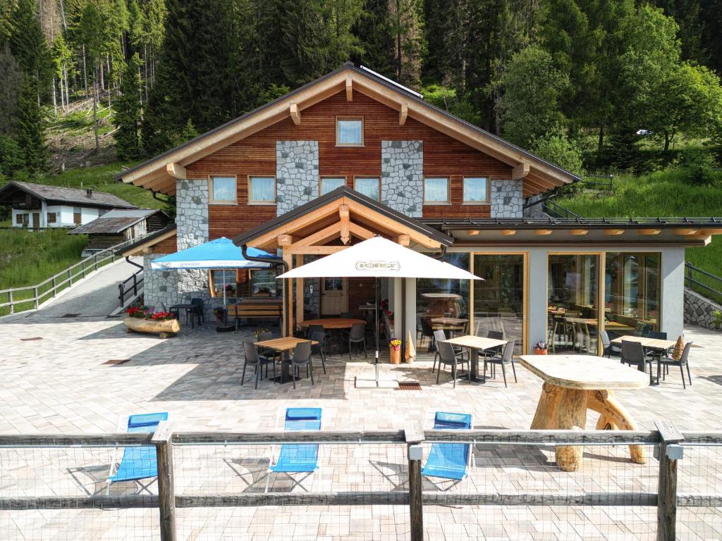 a log cabin with chairs and tables and umbrellas at Hotel Chalet Serena in Roncegno