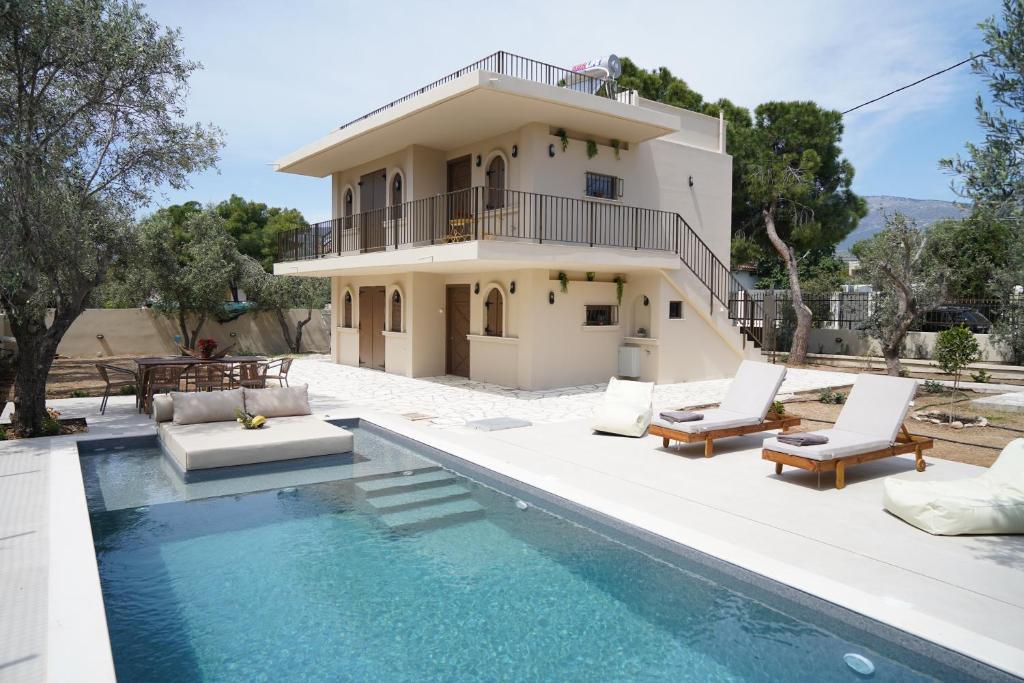 a villa with a swimming pool in front of a house at Villa Noema Kineta in Kineta