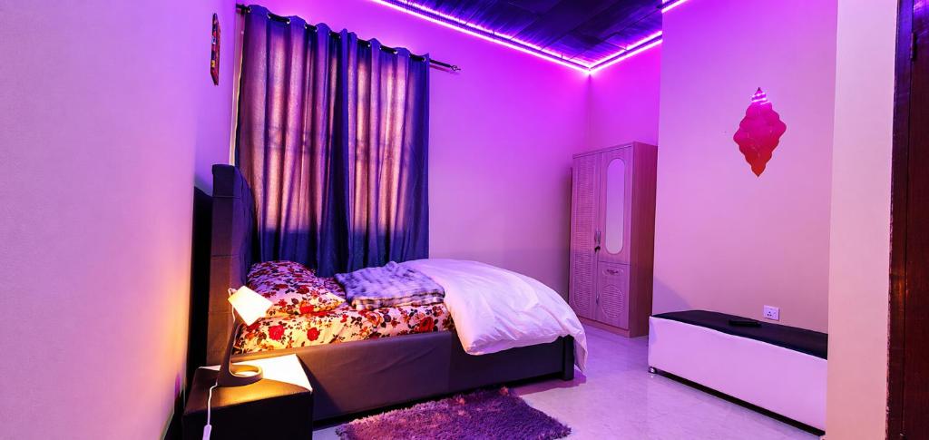 a bedroom with a bed with a purple lighting at cozyairbnb in Otinshi