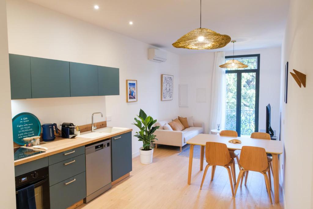 a kitchen and living room with a table and chairs at Les Suites du Parc - Elégance et lumière face au Parc Simone Veil appartement 2 chambres à 2 minutes des halles in Sète