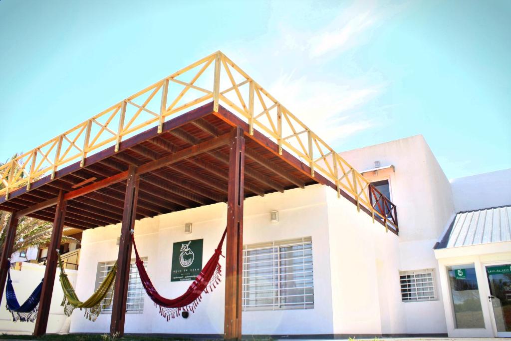 a white building with hammocks in front of it at Agua De Coco in Villa Gesell
