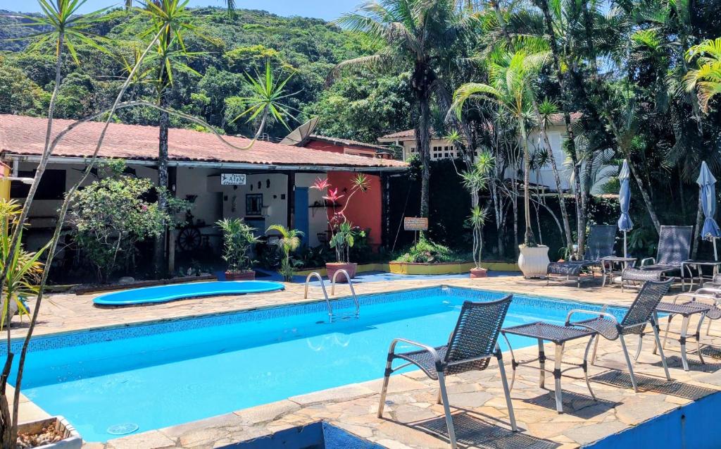 a swimming pool with chairs and a house at Pousada Atobá Juquehy Apartamentos in Juquei