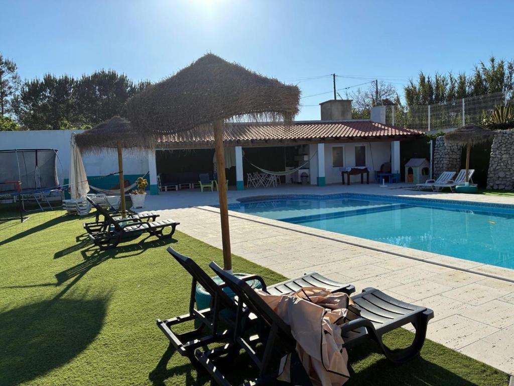a villa with a swimming pool with chairs and a house at Coruche Pool & Jacuzzi Residence - Condomínio Privado in Coruche