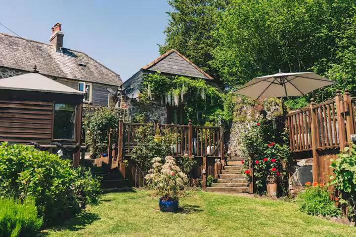 a garden with a wooden fence and an umbrella at Coachman's Cottage B & B in Plymouth