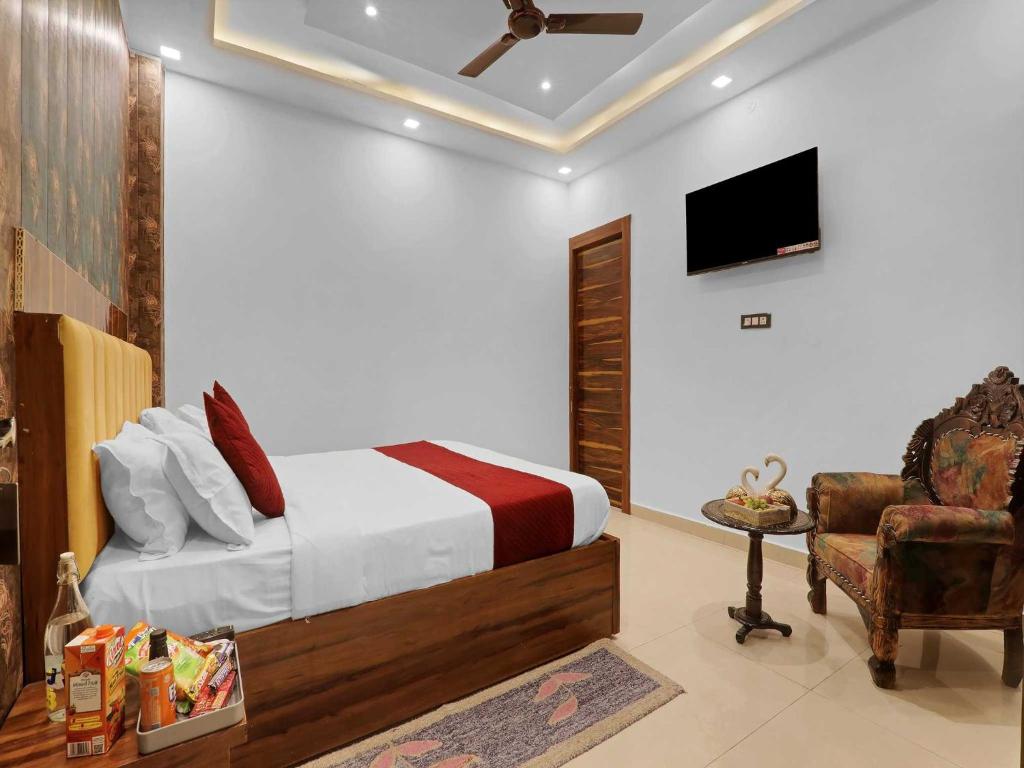 a bedroom with a bed and a tv and a chair at Palette Oraya Greens by CheckIn, Kathauta Lake, Lucknow in Chinhat