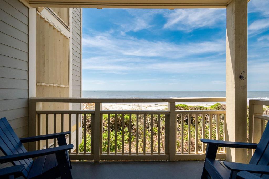 a balcony with chairs and a view of the ocean at Beach Therapy by Oak Island Accommodations in Caswell Beach