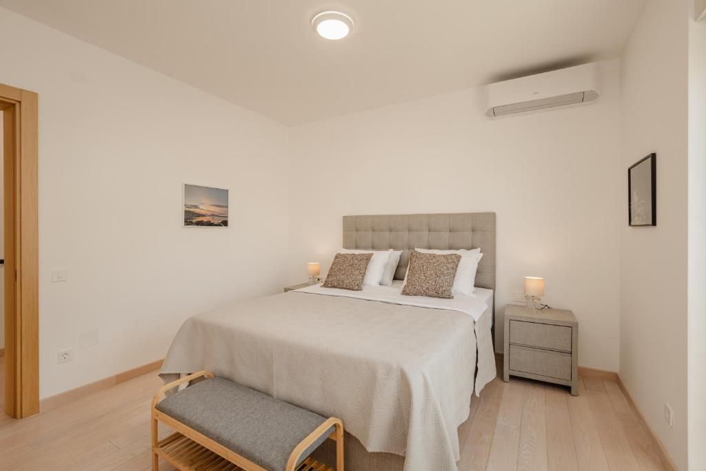 a white bedroom with a large bed and a chair at River side apartment B17 in Herceg-Novi