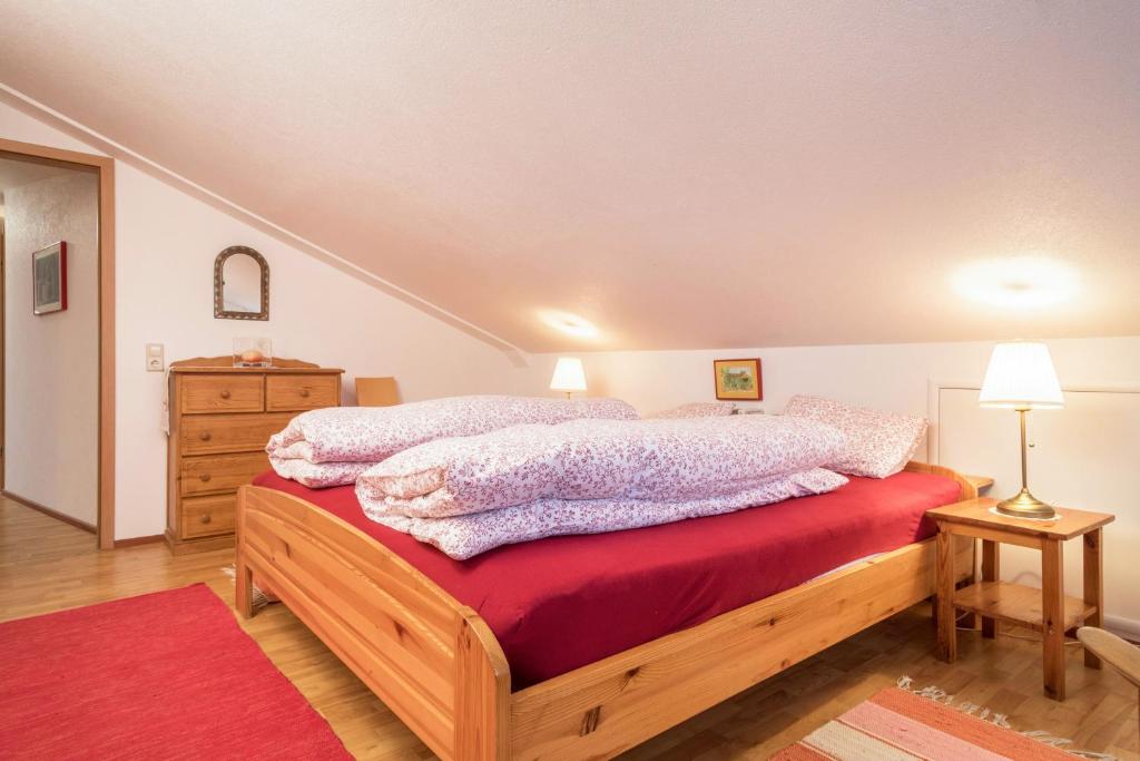 a bedroom with a bed with red sheets and a dresser at Adlerblick in Wangen