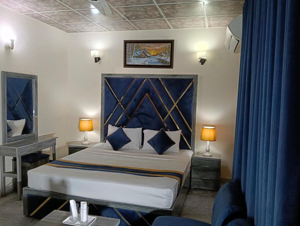 a bedroom with a king sized bed with a blue headboard at Star Hotel Lahore in Lahore