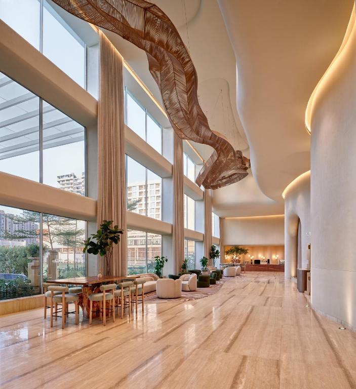 a large lobby with large windows and tables and chairs at The Forum Hotel and Convention in Ahmedabad