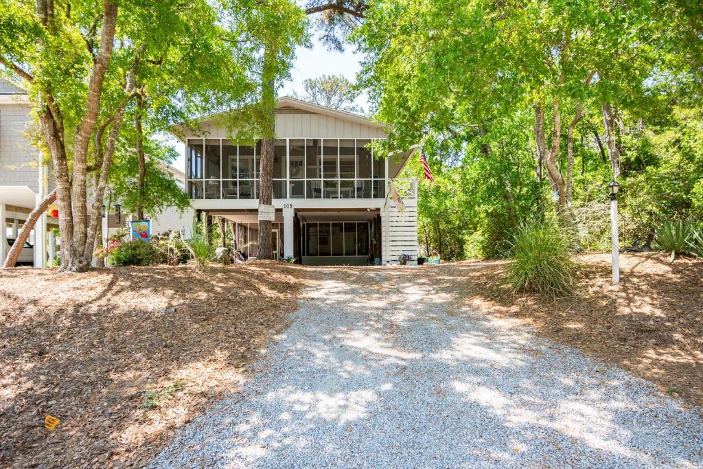 an empty driveway in front of a house with trees at Beaching & Griping by Oak Island Accommodations in Oak Island