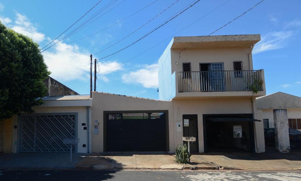 a white house with a gate and a garage at Casa com Churrasqueira e WiFi em Parque Ribeirao in Ribeirão Preto