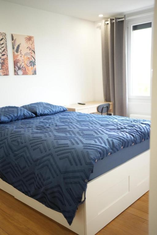 a bedroom with a bed with a blue comforter and a window at Olivia in Argenteuil