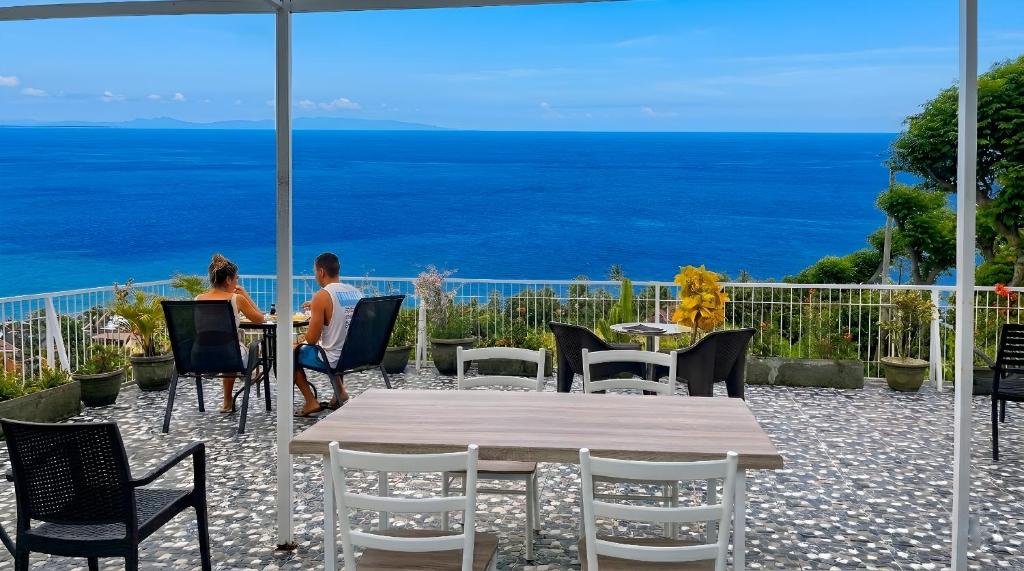 a man and woman sitting at a table looking at the ocean at Arirang Sea View Homestay in Senggigi