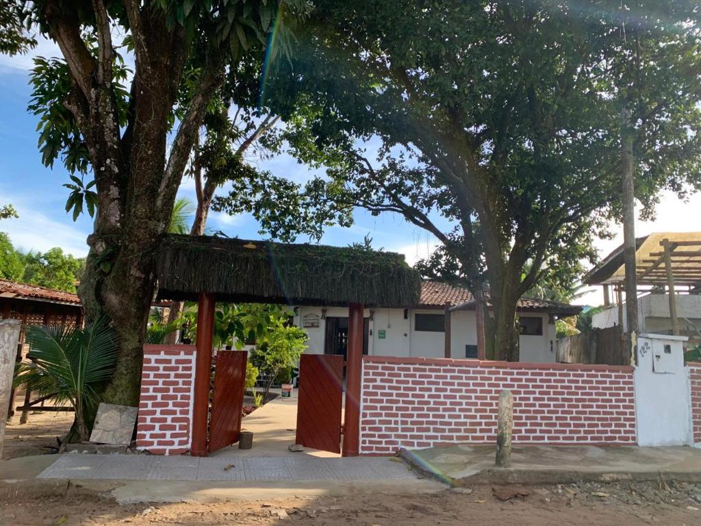a house with a brick fence and a tree at Pousada PauBrasil in Barra Grande