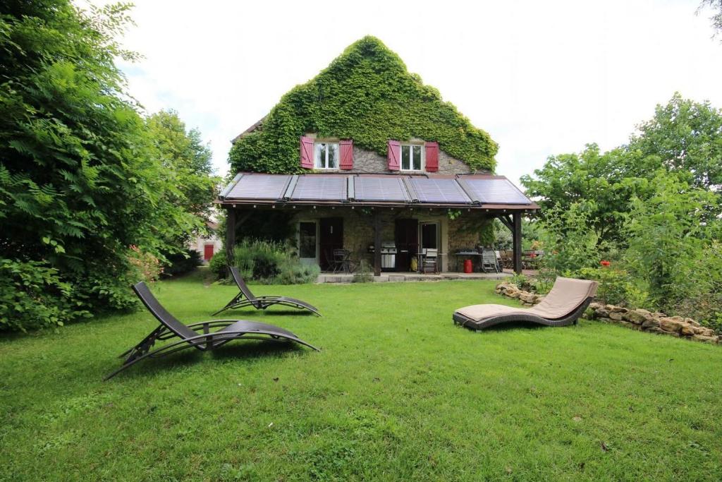a house with chairs in the grass in front of it at La Chaume en Loire in Devay