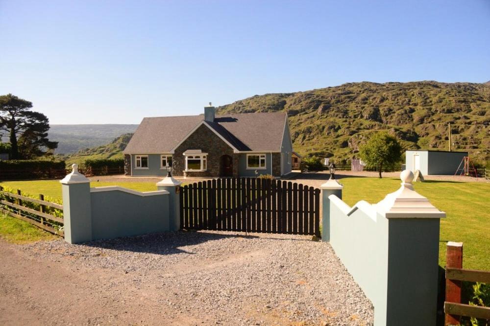 a house with a white fence in front of a yard at Black Valley lodge in Killarney