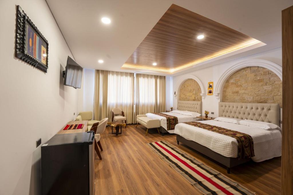 a hotel room with two beds and a desk at Hotel Boutique La Torre in Tupiza