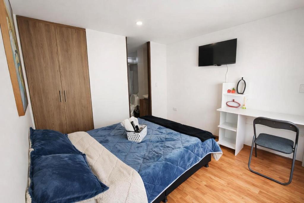 a bedroom with a bed and a chair and a television at Apartaestudio con parqueadero cerca UPTC y Clínica Los Andes in Tunja