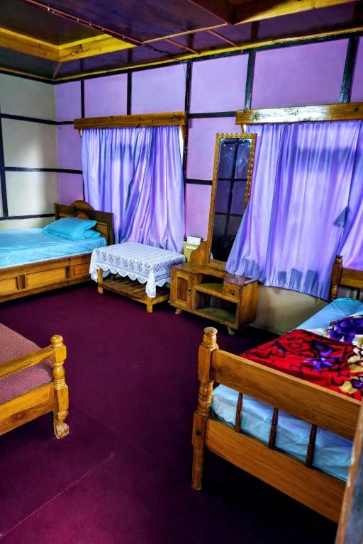 a room with three beds and a purple wall at Green Haven in Kalimpong