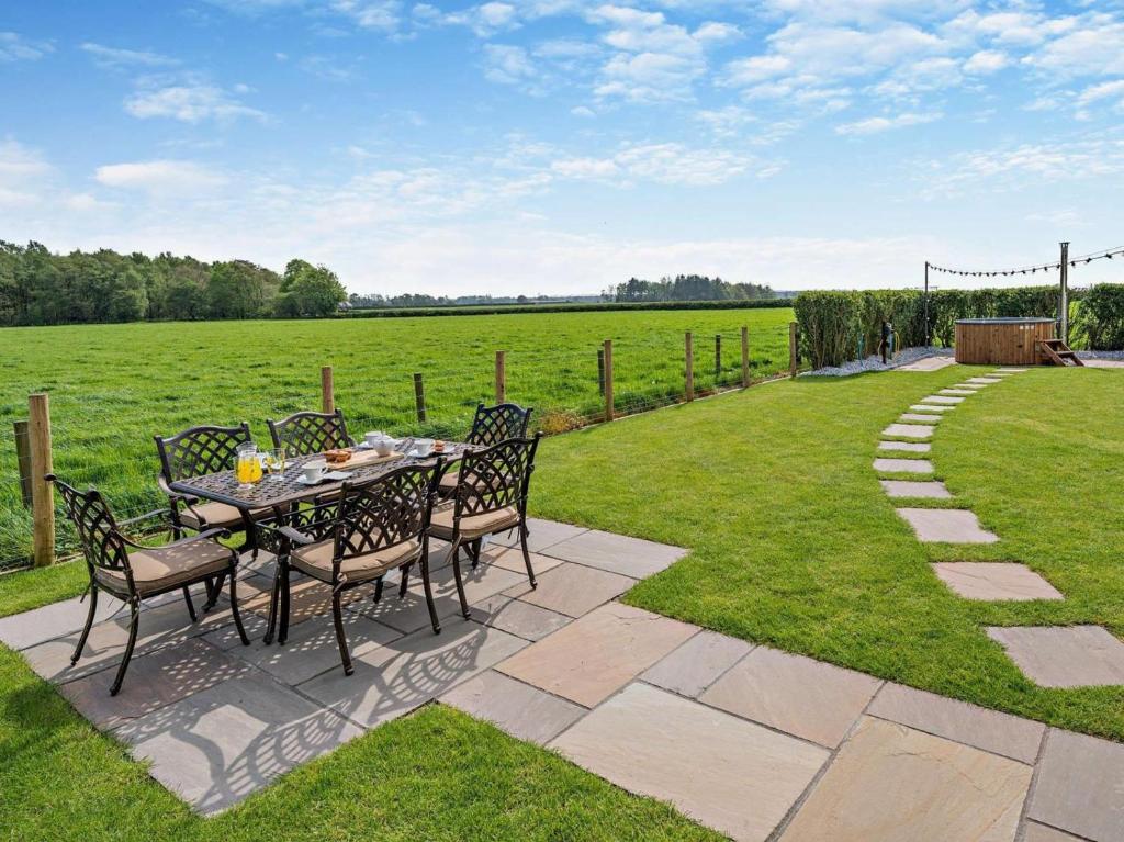 a table and chairs on a lawn with a field at 3 Bed in Carlisle oc-94673 in Longtown