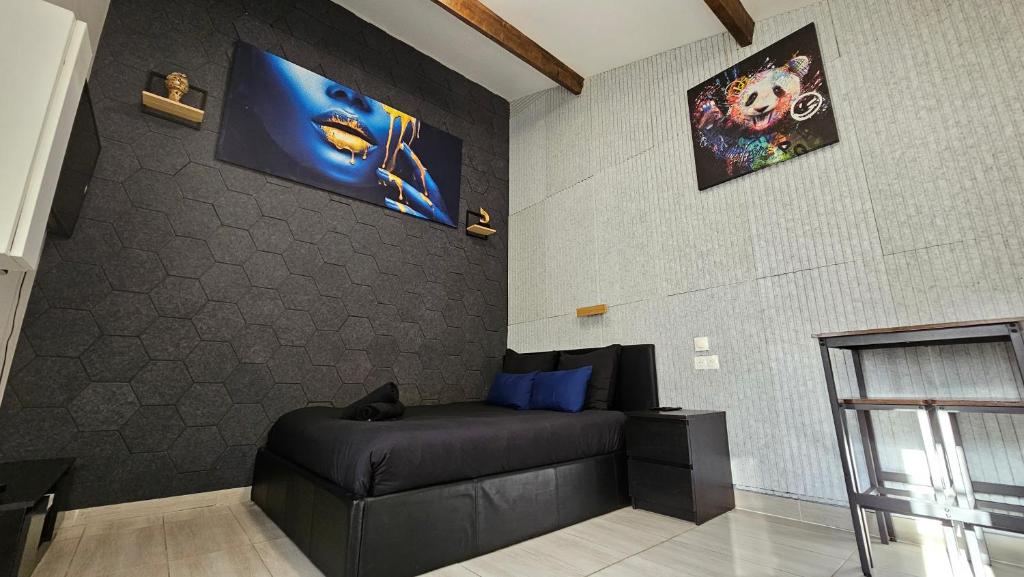 a living room with a black couch and a wall at Maisonnette Grande Hauteur Proche Paris & Stade De France in Drancy