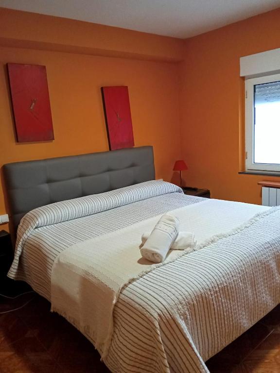a bedroom with a large bed with orange walls at Alojamientos Fermín in Cangas de Onís