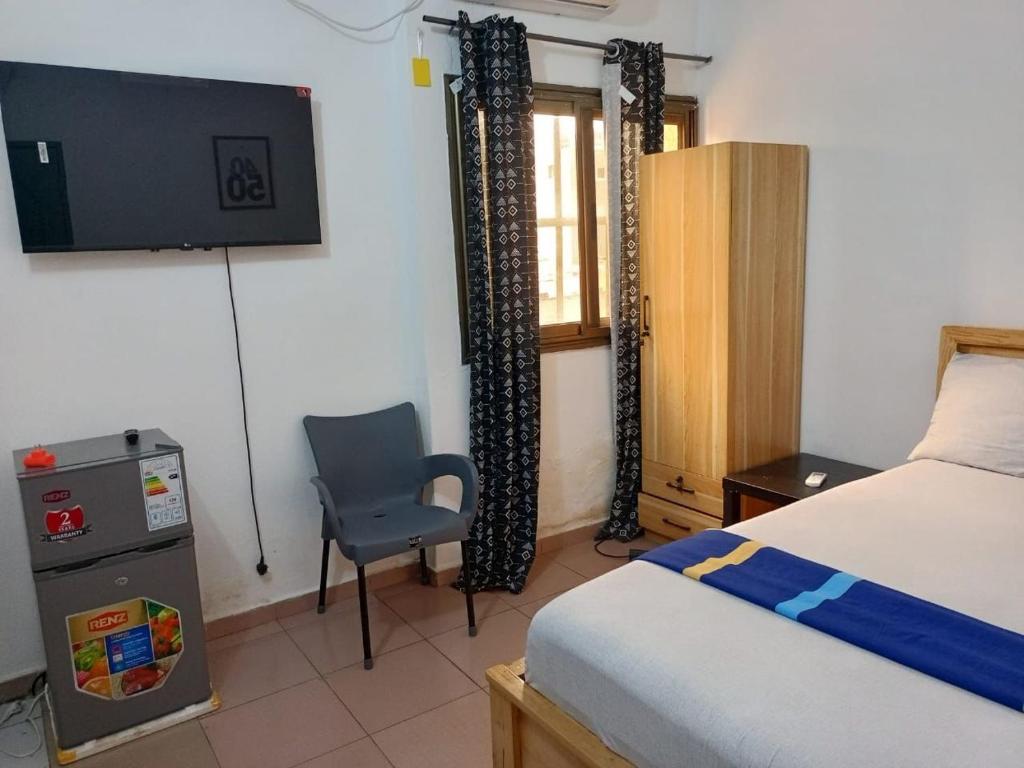a bedroom with a bed and a chair and a television at Guest House HEBERTOGO in Lomé