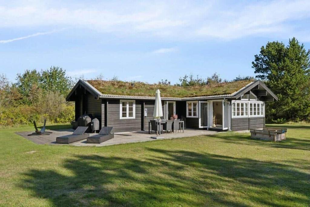 a small house with a patio and an umbrella at TV1721-Jerup-Engsigen-12 in Bratten Strand