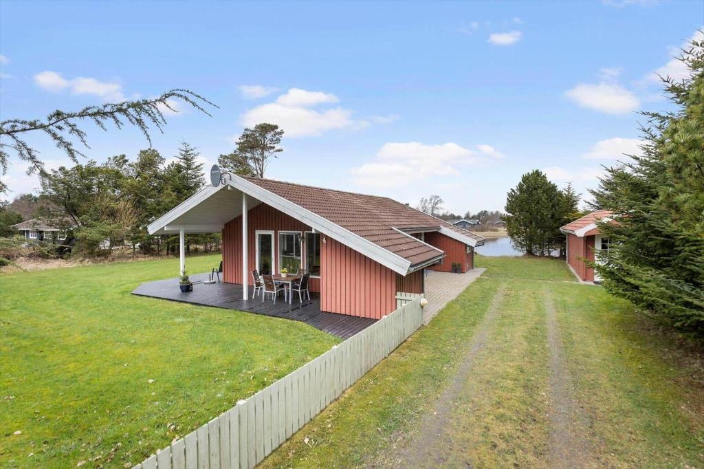 a red house with a deck and a fence at TV1718-Bindslev-Astersvej-4 in Tversted