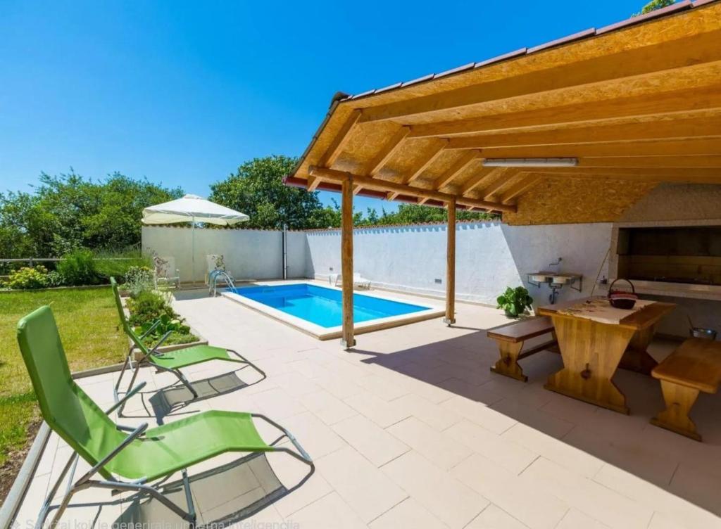 a patio with chairs and a table and a swimming pool at Villa Kapitulac in Grižane