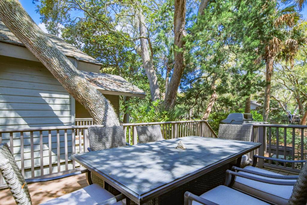 a table and chairs on a deck with trees at Fiddlers Hideaway in Kiawah Island