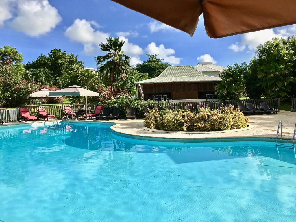 einen Pool in einem Resort mit Stühlen und Sonnenschirmen in der Unterkunft Résidence Le Vallon Guadeloupe Parc Piscine Appartements & Studios & Services hôteliers à la carte in Saint-François