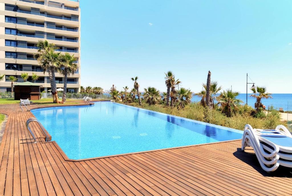 a swimming pool on a wooden deck with a building at Apartment Grape Panorama Mar Punta Prima in Punta Prima