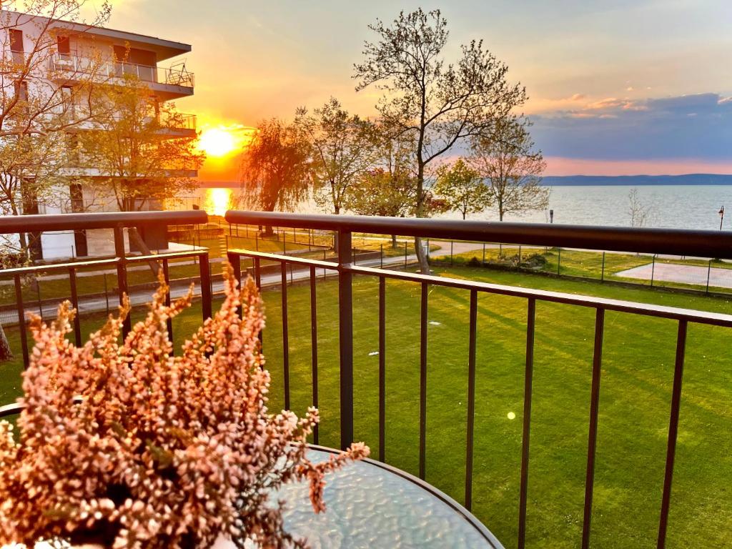 a glass table on a balcony with a view of the water at Siófok Panoráma Apartman in Siófok