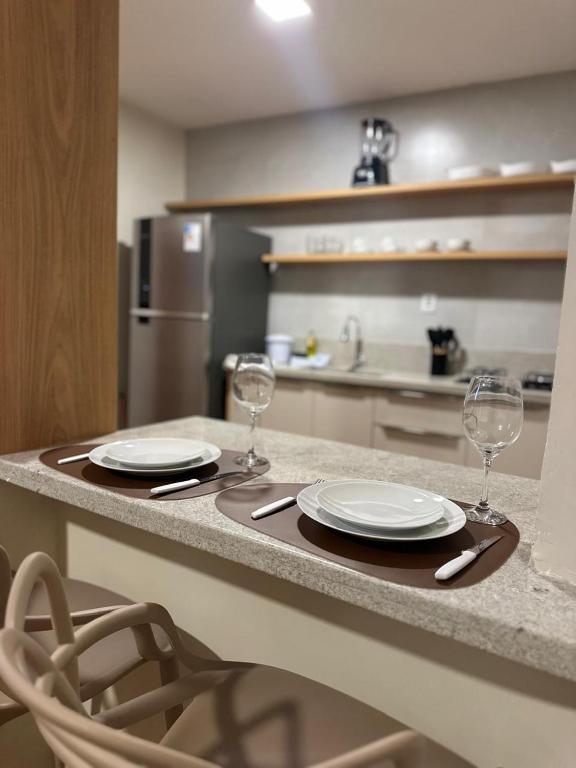 a table with two plates and two wine glasses at Flat com vista mar in Mucuri