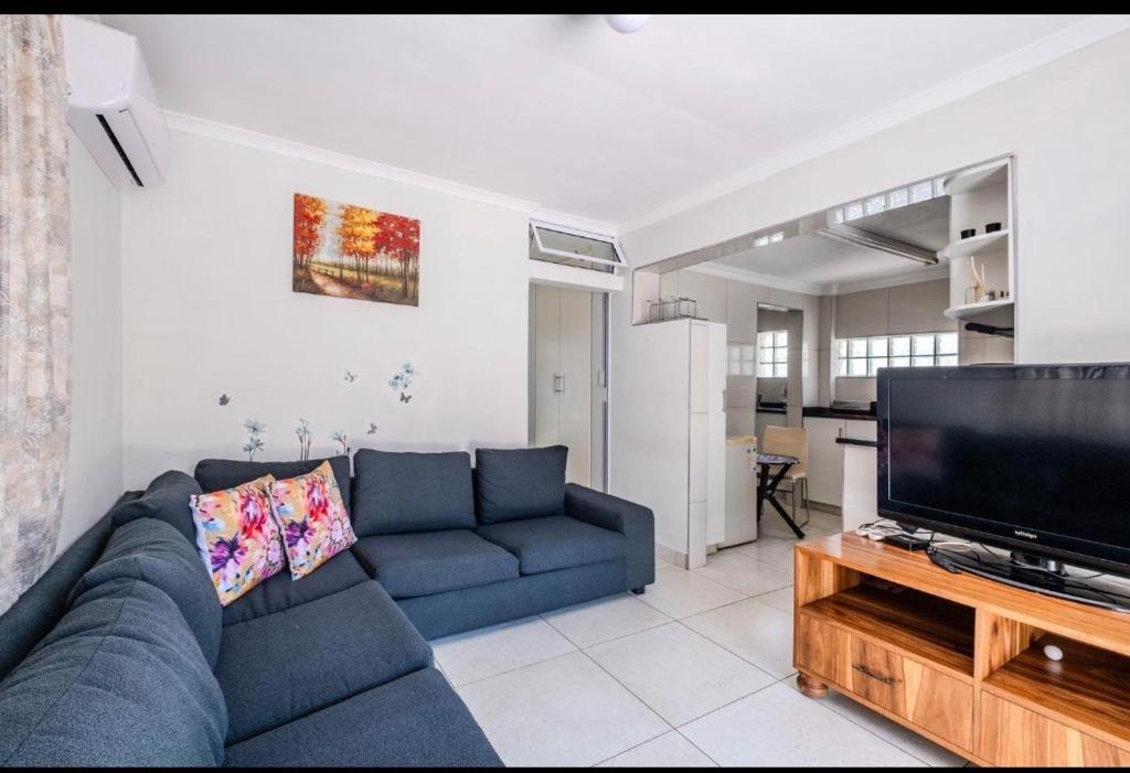 a living room with a blue couch and a flat screen tv at La Lucia Sleepover in Durban