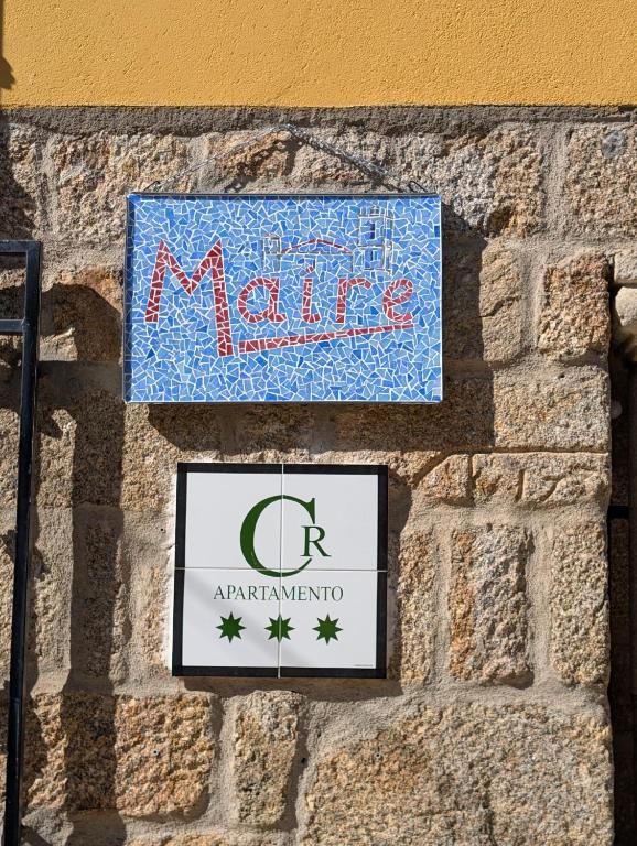 two signs on the side of a stone wall at Casa Rural Maire TR-CC-00590 in Gata