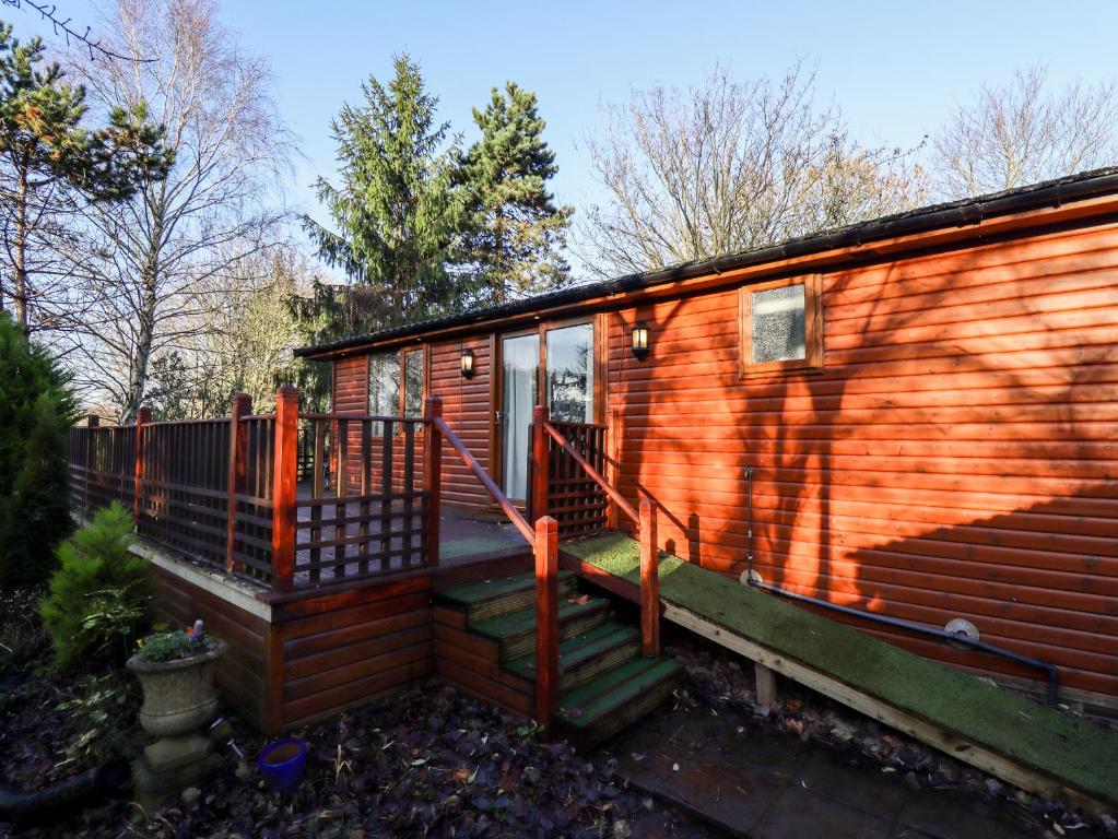 a wooden cabin with a staircase and a house at Kantankye Lodge in Skegness