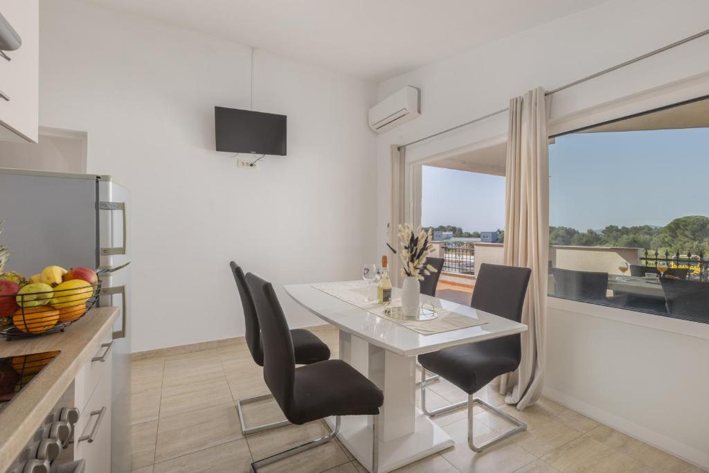 a white dining room with a white table and chairs at Peacefull Apartment with Garden and Barbeque in Biograd na Moru