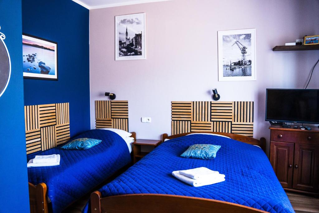 two beds in a room with blue walls at Willa Bliska in Gdańsk